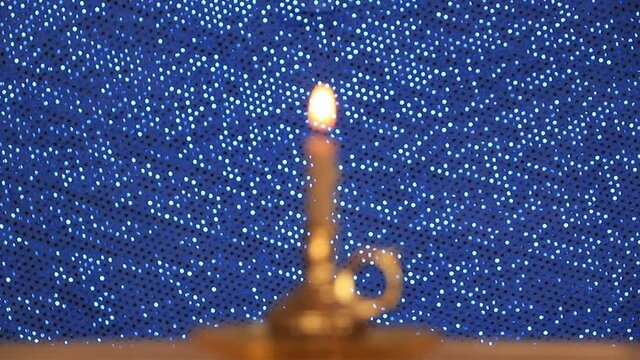 one candle is burning on a blue background, the concept of a prayer to God, faith in a higher power, religion