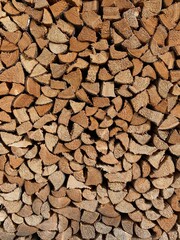 Background with firewood.  Wood detailed texture. Logs of triangular section.  Chopped trunk of oak, maple or birch for a flyer, postcard or banner template. Heating the room in Alpine villages.