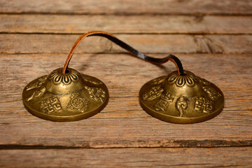 Tingsha. Hand cymbals. Tingsha Cymbal Bell. Karatals. Tibetan bells on wooden background close up.