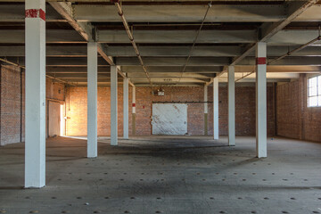 Wide open warehouse space with brick wall and barn door in an abandoned factory