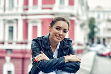 Beautiful young girl in a fashionable leather jacket on a city street