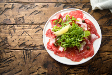 Traditional beef carpaccio with parmesan cheese and arugula