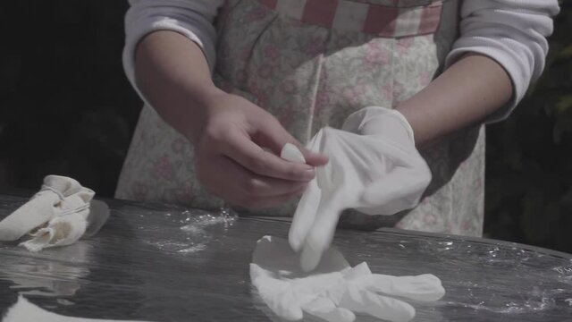 Hands of brunette girl putting on latex gloves to do tie dye technique