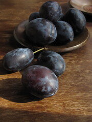 Plums on a wooden plate in a rustic style, still life with plums on a wooden background.  For posters, banners, covers, packaging, printing
