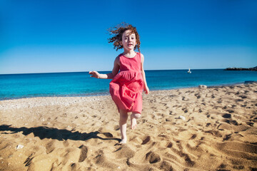 Happy cute little girl running on the beach