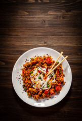 Chicken nuggets, white white rice noodles, soy sauce and vegetables served on wooden table
