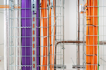 Electrical conduits system and metal pipeline installed on building ceiling. orange and purple wires