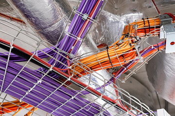 Electrical conduits system and metal pipeline installed on building ceiling. orange and purple wires