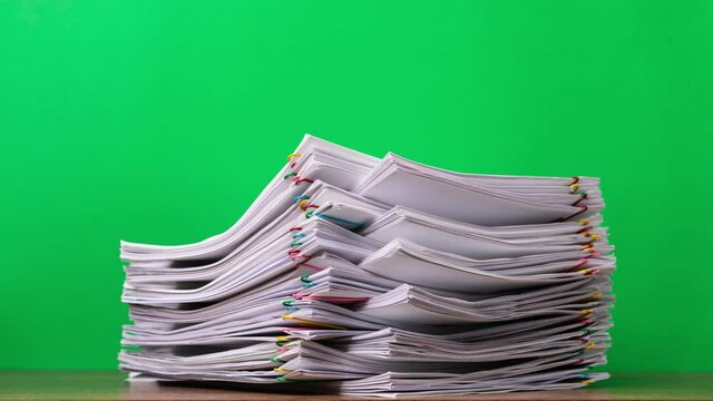 4K Stop of motion close-up stack overload document report paper with paperclip place increase on green background, business and education concept footage paperless used. 