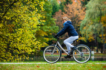 Fototapeta premium Urban biking - woman riding bicycle in city park 