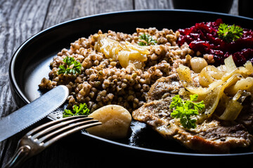 Roasted meat, buckwheat and beetroots on wooden table
