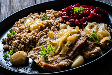 Roasted meat, buckwheat and beetroots on wooden table