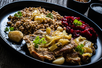 Roasted meat, buckwheat and beetroots on wooden table