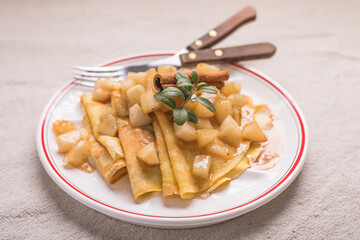 Thin pancakes (crepes) with apple filling, stuffed rolls, Russian traditional food for maslenitsa, French dessert, breakfast with tulips on mother's day