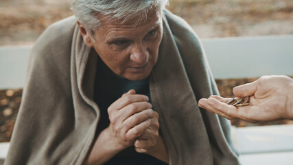 Poor elder homeless man receiving coins from woman. High quality photo