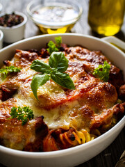 Pasta casserole with minced meat, mozzarella cheese and vegetables on wooden table