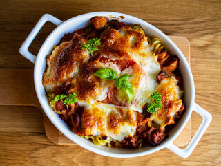 Pasta casserole with minced meat, mozzarella cheese and vegetables on wooden table