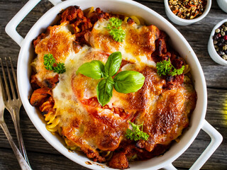 Pasta casserole with minced meat, mozzarella cheese and vegetables on wooden table