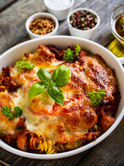 Pasta casserole with minced meat, mozzarella cheese and vegetables on wooden table