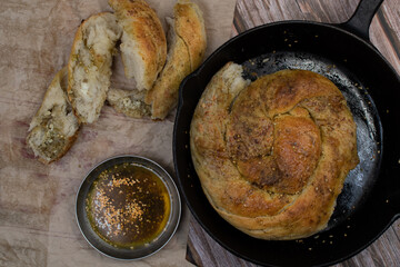 Cheese and zatar bread roll on cast iron pan, wooden table