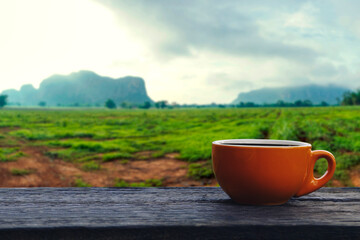 Obraz premium Coffee cup on wood table with a view of mountain landscape and farming