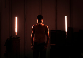 Handsome and strong man portrait posing with light of neon lamps and smoke over dramatic blue neon...
