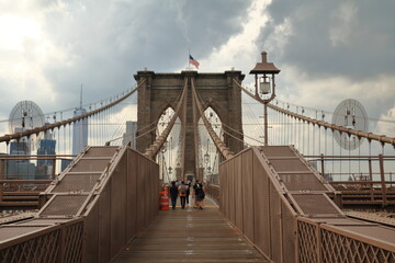 Tourists and residents cross Brooklyn Bridge in New York City, New York. Brooklyn Bridge is one of...