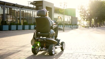 Woman tourist riding a four wheel mobility electric scooter on a city street. 