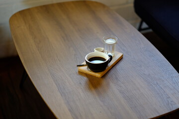 Black coffee cup with water and sugar placed on a wooden table.