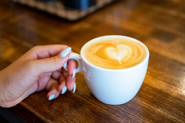 Woman holds a cup of coffee with froth. Cappuccino