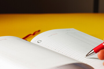 agenda y boligrafo con fondo amarillo, bajo el concepto de trabajo desde casa 