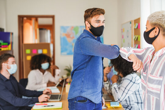 Coworking Office With Safety Measures For Coronavirus - Young People Meet And Greet With Elbow While Wearing Protective Face Mask