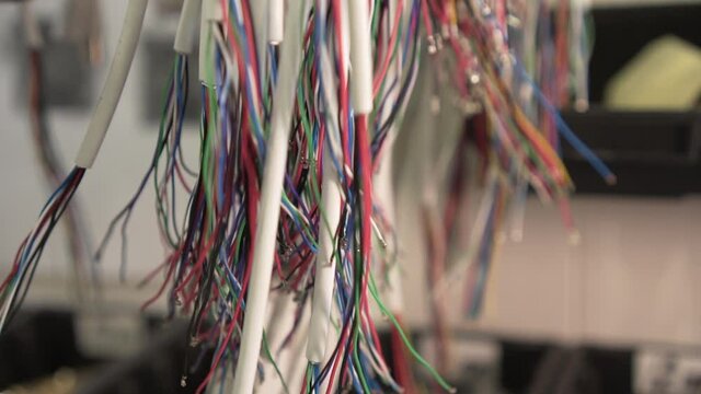 Slow Motion Around Bundles of Colored Wires Hanging in the Workshop. DIY project electronics. Wires jumpers for mockup prototype breadboard plate.