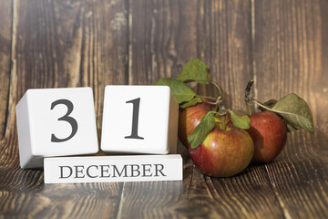 December 31. Day 31 of month. Calendar cube on wooden background with red apples, concept of business and an important event. Winter season.