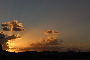 A photograph of a vibrant sunset with sunlight rays filtering out from beautiful fluffy clouds, with copy space