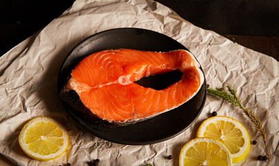 fresh salmon steak in black plate with rosemary pepper and lemon