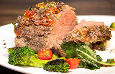 Roasted and seasoned meat with accompaniment of fried egg, brocolis, onion and tomato.