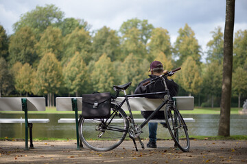 Man enjoys sun on park bench with bicycle. Everyday life during corona quarantine.