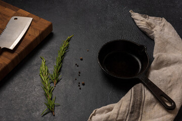 Empty black cast iron frying pan on a dark graphite background. Light linen towel. Wooden end...