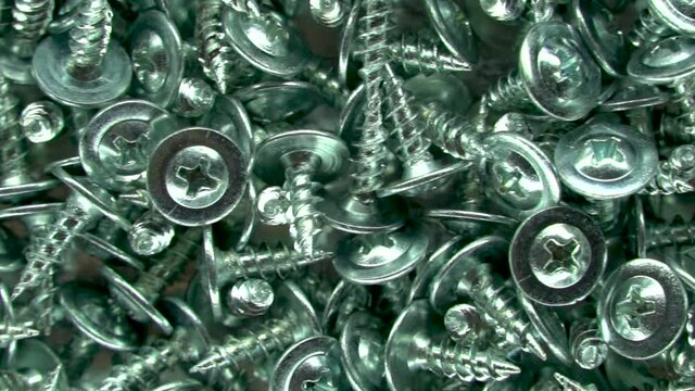 Stainless steel bolts. Metallic texture background. Screws and cogs. Tools for fixing and repairing. Background of the bolts. Galvanized metal fasteners. Close up. The view from the top.