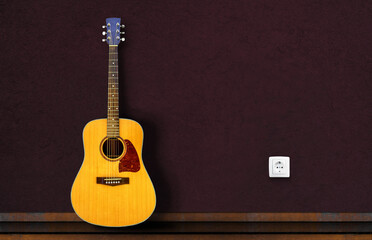 Fototapeta premium Acoustic guitar resting against a dark wall