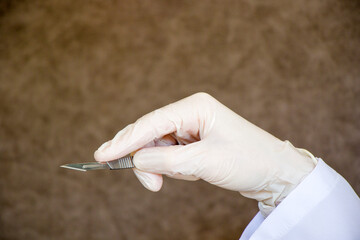 Surgery knife in doctors hand. Operation equipment, hand, glove, and blade.