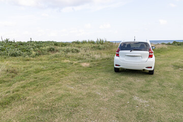 car parked in a meadow near the sea