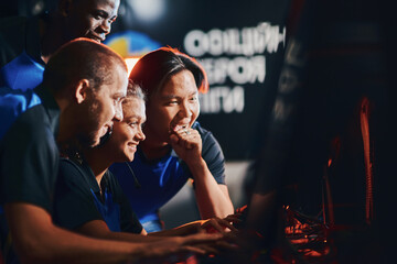 Team of happy professional cybersport gamers looking at PC screen and feeling excited and happy...