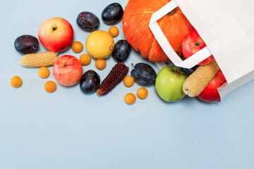 Package with scattered colored fruit on a blue background. Plums, tangerines, lemon, apples, pumpkin. Shopping in the store. the view from the top