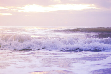 Fototapeta na wymiar Ocean wave on a sandy beach in the morning, Violet tone