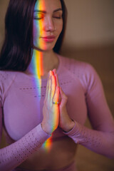 Woman portrait practicing meditation and yoga with rainbow light on her body and face