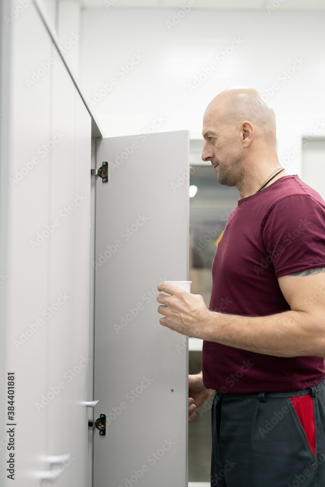 Aufkleber Side view of bald mature worker of factory standing in front of open locker