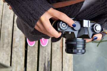 Young caucasian woman holding vintage retro camera outdoors.