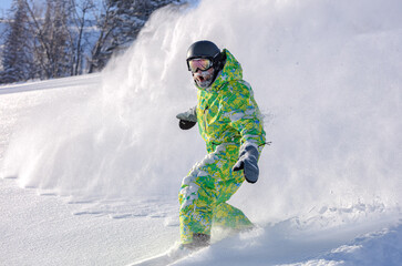 Extreme snowboarder has fun riding fresh powder snow off piste in white mountains. Pro rider...
